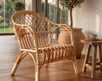 May include: A light brown rattan chair featuring a curved backrest with a diamond-patterned lattice weave, rounded armrests, and a seat constructed from parallel bent rattan poles, with light-colored bindings securing the joints.