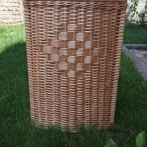 May include: A woven wicker storage basket with a natural brown color. The basket is made of tightly woven strips of wicker and has a rectangular shape.