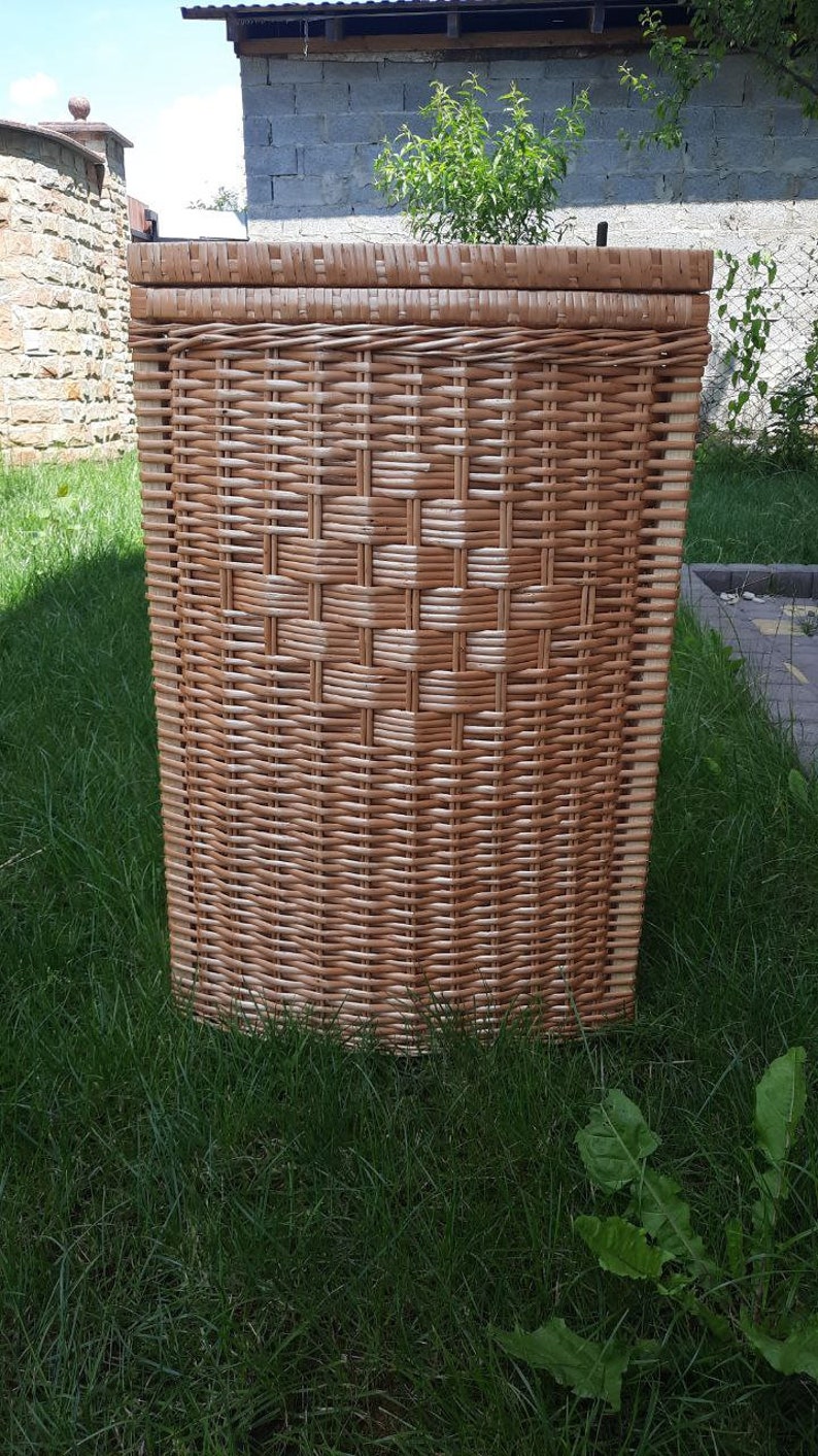 May include: A woven wicker storage basket with a natural brown color. The basket is made of tightly woven strips of wicker and has a rectangular shape.
