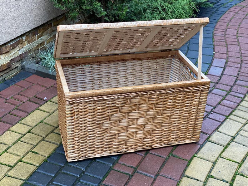 May include: A large, natural woven wicker storage basket with a hinged lid. The lid is open and the basket is empty.