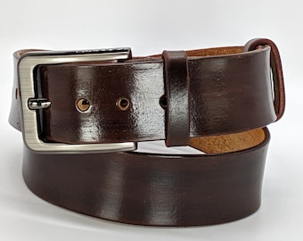May include: A dark brown leather belt with a silver-colored buckle. The belt has a glossy finish and a classic design, suitable for various outfits. The buckle is rectangular with a single prong.