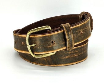 May include: A brown leather belt with a brass buckle. The belt has a distressed look, with a faded brown color and a worn texture.
