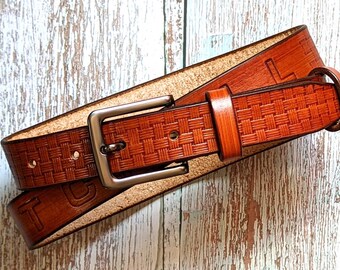 May include: A brown leather belt with a woven pattern and a silver buckle. The belt has a letter 'L' embossed on it.