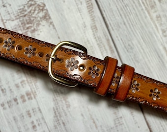 May include: A brown leather belt with a floral design and a gold buckle.