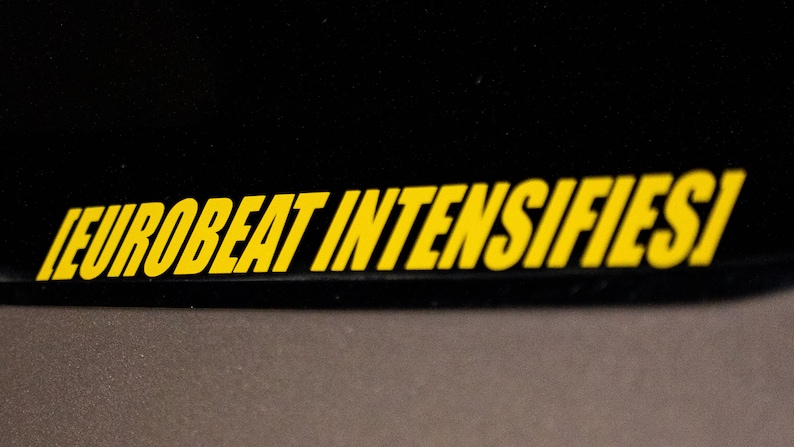 Może przedstawiać: Czarna powierzchnia z tekstem "EUROBEAT INTENSIFIES!" w ż&oacute;łtych literach.