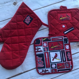 May include: Set of three red quilted pot holders with a St. Louis Cardinals theme. One pot holder has a red cardinal and baseball bat, another has a baseball and the team logo, and the third has the team's initials.