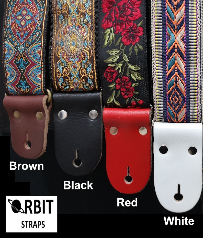 Colorful collection of woven guitar straps showing brown, black, red, and white leather ends. Handmade floral and geometric designs for unique musician style.