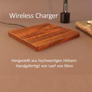 Puede incluir: Un cargador inalámbrico de madera con el texto "Wireless Charger" encima. El texto debajo del cargador dice "Hergestellt aus hochwertigen Hölzern Handgefertigt von Leef von Rönn".
