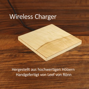 Puede incluir: Un cargador inalámbrico de madera con un acabado de madera clara. El cargador está sobre una superficie de madera. El texto "Wireless Charger" está encima del cargador. El texto "Hergestellt aus hochwertigen Hölzern Handgefertigt von Leef von Rönn" está debajo del cargador.