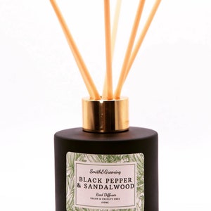May include: Black glass bottle with a gold lid and wooden diffuser sticks. The label reads "Smith & Greening Black Pepper & Sandalwood Reed Diffuser Vegan & Cruelty Free 100ml".