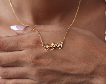 May include: A gold-toned necklace featuring a pendant composed of four distinct hand shapes forming letters in American Sign Language. The delicate chain connects to the top of the hand-shaped metal cutout, creating a continuous horizontal design.