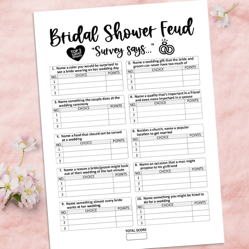 Puede incluir: Una hoja de juego de papel blanco titulada "Bridal Shower Feud" con preguntas para completar sobre bodas. La hoja de juego incluye una secci&oacute;n para los resultados de la encuesta y una puntuaci&oacute;n total. Flores decorativas en el fondo.