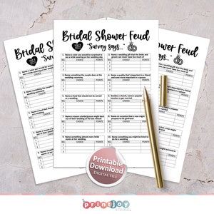 Puede incluir: Hojas de juego imprimibles de Bridal Shower Feud con preguntas para completar. Las hojas tienen un dise&ntilde;o en blanco y negro con el texto "Bridal Shower Feud" y "Survey says..." impreso en ellas. Un bol&iacute;grafo dorado descansa sobre las hojas.