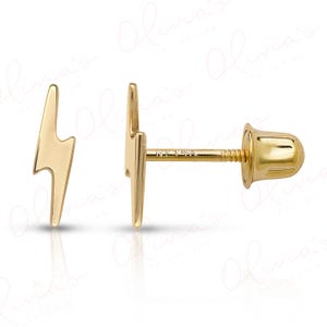 May include: A pair of gold-colored lightning bolt stud earrings. One earring is shown from the side, displaying the post and screw-on backing. The other earring is shown from the front. The earrings are set against a white background.