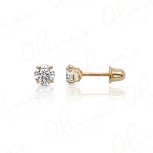 May include: A pair of gold stud earrings featuring round, clear, faceted stones set in four-prong gold settings. The earrings include threaded posts and matching gold screw-back closures, with the text 14K visible on the earring post.