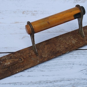 Puede incluir: Una manija de puerta vintage con una placa de metal oxidada y una perilla de madera amarilla.