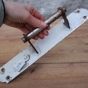 Könnte beinhalten: Weißer Türknauf aus Metall mit einem langen, silbernen Metallhebel. Der Knauf hat ein Schlüsselloch und ein dekoratives Design.