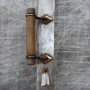 Könnte beinhalten: Ein antiker silberner Türgriff mit einem Holzknopf. Der Griff hat ein Schlüsselloch und dekorative Details. Der Griff ist leicht angelaufen und zeigt Gebrauchsspuren.