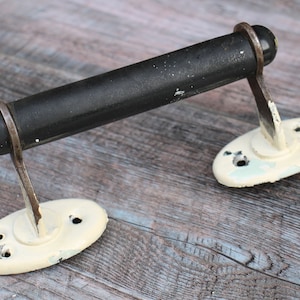 May include: A black metal towel bar with white painted metal brackets. The bar is attached to the brackets with screws. The brackets have three holes each.