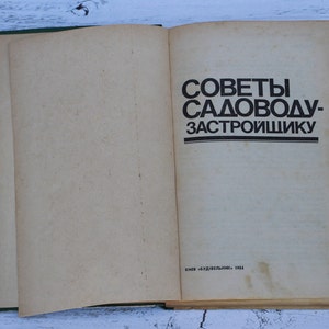 May include: An open book with a green cover. The title of the book is "Советы садоводу-застройщику" which translates to "Advice for the gardener-developer". The book was published in 1984.