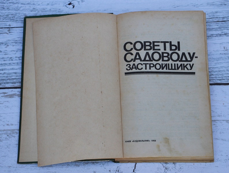 May include: An open book with a green cover. The title of the book is "Советы садоводу-застройщику" which translates to "Advice for the gardener-developer". The book was published in 1984.