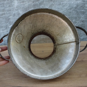 May include: A vintage metal funnel with a wide opening and a narrow spout. The funnel has two handles and is made of silver-colored metal.
