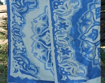 Peut inclure: Un textile rectangulaire présentant un motif floral répétitif bleu et blanc cassé. Le design se compose de grandes fleurs stylisées et de motifs de feuilles complexes disposés de manière symétrique sur la surface du tissu, créant un contraste marqué.