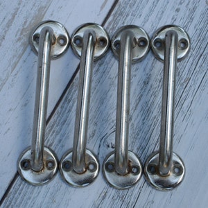 May include: Four silver door handles with a rounded rectangular shape. The handles have a smooth, polished finish.