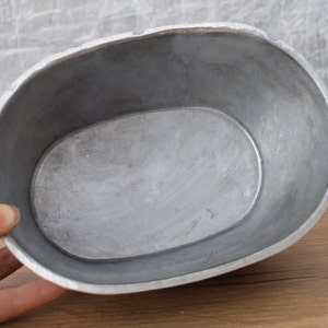 May include: A silver oval-shaped metal baking dish with a smooth, shiny surface.