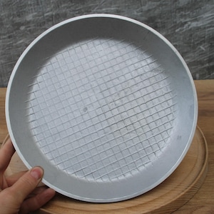 May include: A silver aluminum frying pan with a grid pattern on the bottom.