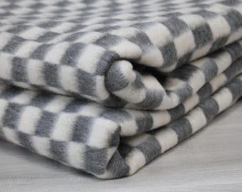 Peut inclure: Couverture pliée avec un motif à carreaux gris et blanc. Le tissu doux et moelleux est plié, révélant la texture et le design. La couverture est de couleur neutre, adaptée à divers styles de décoration intérieure.