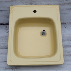 May include: A yellow enamel kitchen sink with a single drain hole and a small diamond-shaped hole at the top.