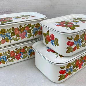 May include: Four white enamelware nesting storage containers with a floral design featuring red and blue berries, green leaves, and pink and red strawberries.