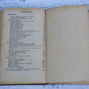 May include: A close-up of a book's table of contents, titled "Oglavienye" in Russian. The page lists various topics related to gardening and home improvement, including general questions, construction, planting, and care.