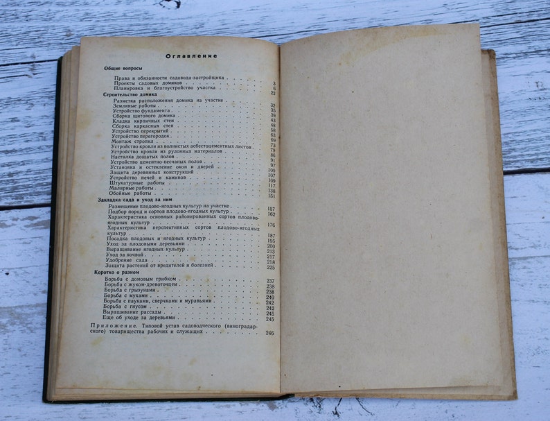 May include: A close-up of a book's table of contents, titled "Oglavienye" in Russian. The page lists various topics related to gardening and home improvement, including general questions, construction, planting, and care.