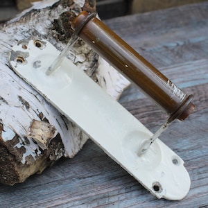 May include: White porcelain toilet paper holder with a brown metal roller. The holder has a rectangular base and a curved arm.