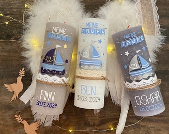 May include: Three white candles with blue and gray designs. Each candle has a different name and date on it. The names are Finn, Ben, and Oskar. The dates are 3.03.2024, 31.03.2024, and 28.01.2024. The candles are decorated with a sailboat, stars, and hearts.