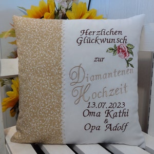 Könnte beinhalten: Ein weißes Kissen mit beigefarbenem Rand und einem dekorativen Muster. Das Kissen ist mit dem Text "Herzlichen Glückwunsch zur Diamantenen Hochzeit 13.07.2023 Oma Kathi & Opa Adolf" bestickt.