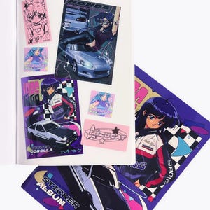Könnte beinhalten: Ein offenes Sticker-Album mit verschiedenen Aufklebern im Anime-Stil. Die Aufkleber zeigen Autos, Charaktere und Text in einer Farbpalette aus Rosa, Lila, Weiß und Schwarz. Das Album liegt auf einer weißen Oberfläche.