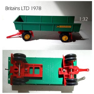Könnte beinhalten: Ein grüner Spielzeug-Traktoranhänger mit roten und gelben Akzenten. Der Anhänger hat eine rechteckige Ladefläche und ist mit "Britains LTD 1978" und "1:32" beschriftet. Die Räder sind schwarz und gelb. Die Unterseite des Anhängers ist ebenfalls sichtbar.