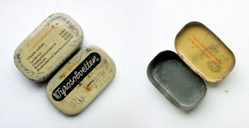 May include: Two vintage metal tins, one open and one closed. The closed tin is labeled "Tyrosolvetten" and has a yellow and white design. The open tin is labeled "T&auml;glich mehrmals 1 Pastille im Munde zergehen lassen" and has a yellow and white design.
