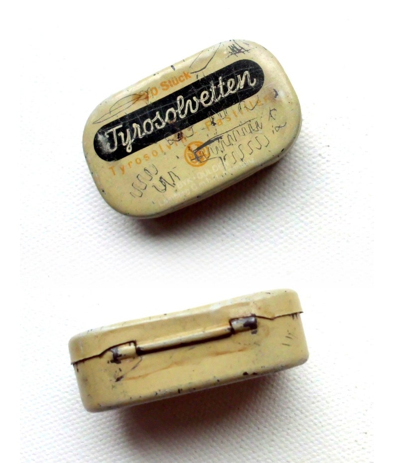 May include: A vintage metal tin with a hinged lid. The tin is cream colored with black lettering that reads "Tyrosolvetten 20 Stuck".