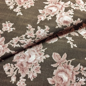 Könnte beinhalten: Nahaufnahme eines Stoffes mit floralem Muster. Das Design zeigt große, hellrosa Rosen und kleinere Blüten auf einem dunkelbraunen Hintergrund. Der Stoff ist gefaltet und zeigt seine Textur und Tiefe.