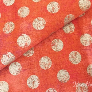 Peut inclure: Gros plan sur un tissu avec un motif r&eacute;p&eacute;t&eacute; de grands pois blanc cass&eacute; sur un fond orange vif. Le tissu a un aspect textur&eacute; avec de subtiles variations de couleur, cr&eacute;ant une surface visuellement int&eacute;ressante.