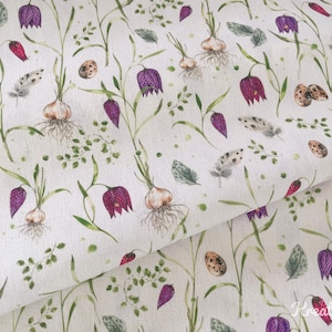 May include: Fabric with a watercolor floral pattern featuring purple flowers, green leaves, bulbs, speckled eggs, and feathers on a cream background. The design has a botanical theme, with a delicate and artistic style.