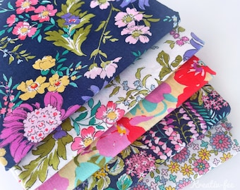 Könnte beinhalten: Ein Stapel Stoffmuster mit Blumenmustern in verschiedenen Farben. Die Stoffe zeigen Muster aus rosa, gelben und lila Blumen mit grünen Blättern auf marineblauen, weißen und roten Hintergründen. Die Stoffe sind ordentlich gefaltet und gestapelt.