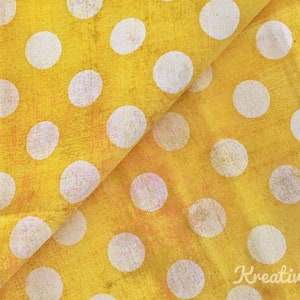 Peut inclure: Tissu jaune vif orn&eacute; de grands pois blancs. Le tissu est pli&eacute;, r&eacute;v&eacute;lant la texture et les variations de couleur. L'image a un aspect vintage ou vieilli.