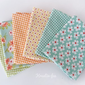 Könnte beinhalten: Eine Sammlung gefalteter Stoffquadrate in verschiedenen Mustern und Farben. Die Stoffe weisen florale, geometrische und karierte Designs in Grün-, Orange-, Gelb- und Blautönen auf. Die Stoffe sind fächerförmig angeordnet.