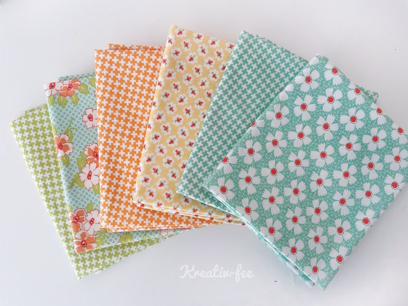 K&ouml;nnte beinhalten: Eine Sammlung gefalteter Stoffquadrate in verschiedenen Mustern und Farben. Die Stoffe weisen florale, geometrische und karierte Designs in Gr&uuml;n-, Orange-, Gelb- und Blaut&ouml;nen auf. Die Stoffe sind f&auml;cherf&ouml;rmig angeordnet.