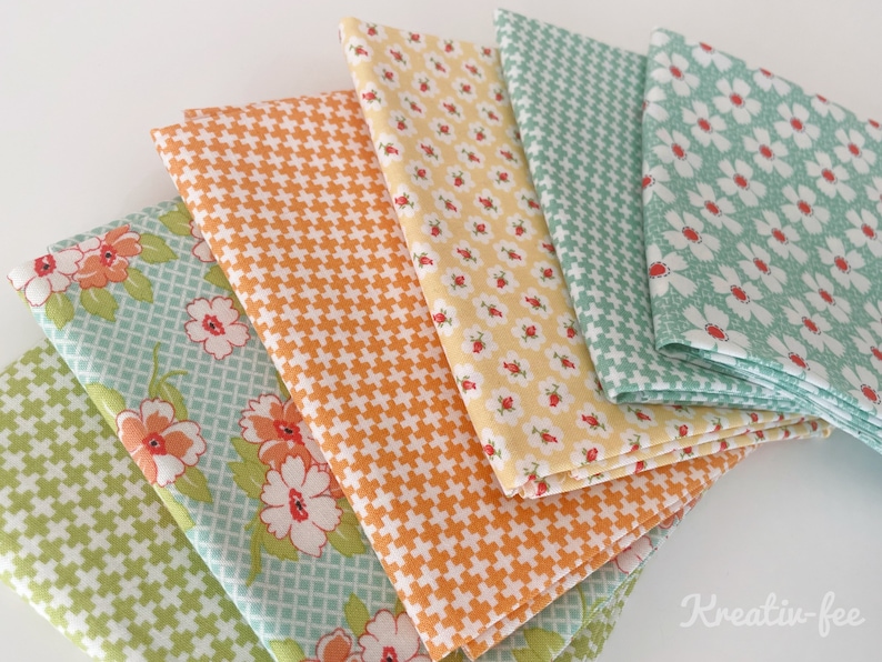 K&ouml;nnte beinhalten: Eine Sammlung gefalteter Stoffquadrate in verschiedenen Mustern und Farben. Die Stoffe weisen florale, geometrische und Kreuzschraffur-Designs in Orange-, Gelb-, Gr&uuml;n- und Blaut&ouml;nen auf. Die Stoffe sind f&auml;cherf&ouml;rmig angeordnet.